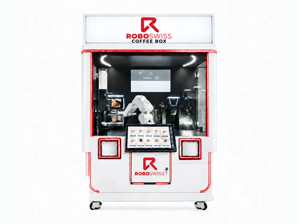 La macchina CoffeeBOX: braccio robotico dietro il vetro, schermo tattile per ordinare e due sportelli di consegna.
